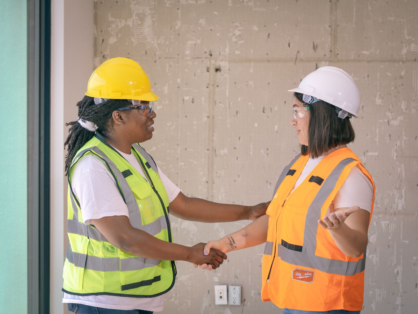 Two engineers in hard hats shaking hands